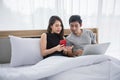 Asian Couple shopping online and paying with credit card on laptop and mobile phone at home,Happy couple at home surfing the net Royalty Free Stock Photo