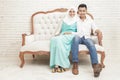 Asian couple sitting on sofa while looking at camera Royalty Free Stock Photo