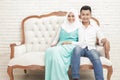 Asian couple sitting on sofa while looking at camera Royalty Free Stock Photo