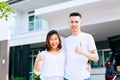 Asian couple standing in front of their new house and giving thumbs up Royalty Free Stock Photo