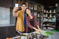 asian couple taking selfie while cooking together in the kitchen Royalty Free Stock Photo