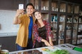 asian couple taking selfie while cooking together in the kitchen Royalty Free Stock Photo