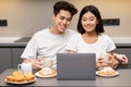 Asian Couple Watching Movie On Laptop In Kitchen Enjoying Breakfast Royalty Free Stock Photo