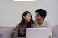 Asian couple watching movies on the internet using laptop at home Smiling Thai man and woman sitting on sofa, hugging Royalty Free Stock Photo