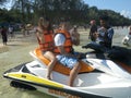 Asian Couple wearing life jackets are posing on a jet ski in the sea. They are close to the shore and about to ride it. - Phuket