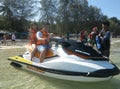 Asian Couple wearing life jackets are posing on a jet ski in the sea. They are close to the shore and about to ride it. - Phuket