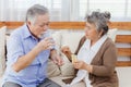 Asian couple woman caring sick old man by giving pill or drug at home