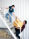 Asian couple young woman frightened and shocked man who carrying and holding cardboard and parcel box fall down from white ladder Royalty Free Stock Photo