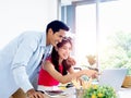 Asian couple, young woman and man looking and pointing at laptop computer screen on desk together. Royalty Free Stock Photo