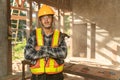 Asian craftsman with holding a hammer in hands standing in spacious workshop and looking at camera on construction site