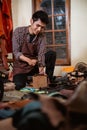 asian craftsman making holes in leather belts with hammer