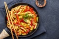 Asian cuisine dish, stir fry chicken, paprika and zucchini, ginger, garlic with sesame and soy sauce in a frying pan. Black table Royalty Free Stock Photo