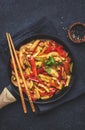 Asian cuisine dish, stir fry chicken, paprika and zucchini, ginger, garlic with sesame and soy sauce in a frying pan. Black table Royalty Free Stock Photo