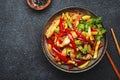 Asian cuisine, stir fry with chicken, red paprika pepper and zucchini bowl. Black kitchen table background, top view, copy space Royalty Free Stock Photo