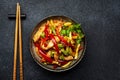 Asian cuisine, stir fry with chicken, red paprika pepper and zucchini bowl. Black kitchen table background, top view, copy space Royalty Free Stock Photo