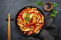 Asian cuisine, stir fry with chicken, red paprika pepper and zucchini in frying pan. Black kitchen table background, top view, Royalty Free Stock Photo