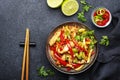 Asian cuisine, stir fry chicken, red paprika and zucchini with sesame and soy sauce in bowl. Black table background, top view, Royalty Free Stock Photo