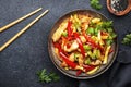 Asian cuisine, stir fry chicken, red paprika and zucchini with sesame and soy sauce in bowl. Black table background, top view, Royalty Free Stock Photo