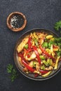 Asian cuisine, stir fry chicken, red paprika and zucchini with sesame and soy sauce in bowl. Black table background, top view, Royalty Free Stock Photo
