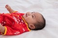 Asian cute baby boy Chinese Cheongsam costume toddler lie down on bed at home smiling laughing good humored infant Chinese