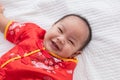 Asian cute baby boy Chinese Cheongsam costume toddler lie down on bed at home smiling laughing good humored infant Chinese