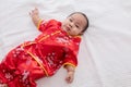 Asian cute baby boy Chinese Cheongsam costume toddler lie down on bed at home smiling laughing good humored infant Chinese