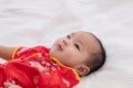 Asian cute baby boy Chinese Cheongsam costume toddler lie down on bed at home smiling laughing good humored  infant Chinese Royalty Free Stock Photo