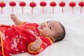 Asian cute baby boy Chinese Cheongsam costume toddler lie down on bed at home smiling laughing good humored infant Chinese boy