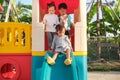 Asian cute brother and sisters having fun playing on a slide in playground at home backyard