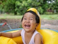 Asian cute child boy laughing while playing outdoor in yellow duck rubber band with rural nature background. Royalty Free Stock Photo