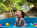 Asian cute child boy laughing while playing water in blue bowl with relaxing face and wet hair in rural nature. Royalty Free Stock Photo