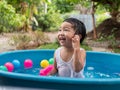 Asian cute child boy laughing while playing water in blue bowl with relaxing face and wet hair in rural nature. Royalty Free Stock Photo