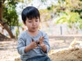 Asian cute child boy playing clay outdoor with funny face in garden.