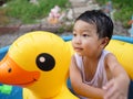 Asian cute child boy playing outdoor in yellow duck rubber band with rural nature background. Royalty Free Stock Photo