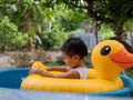 Asian cute child boy playing water in blue bowl in rural nature. Young kid having happy moment in summer. Royalty Free Stock Photo