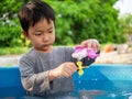 Asian cute child boy playing water and toy in blue bowl with relaxing face in rural nature. Royalty Free Stock Photo