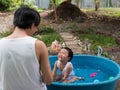 Asian cute child boy smiling while playing water in blue bowl with father in rural nature. Royalty Free Stock Photo