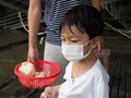 Asian cute child prepare to feed bread to fish with wearing face mask protecting from covid-19.