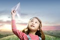 Asian cute girl in an aviator cap with a paper plane with a sunset sky background