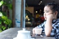 Asian cute girl drinking milk and use smartphone in coffee shop.