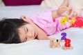 Asian cute girl lying playing wooden toys on a soft white mattress. Adorable kid play number train. Little child`s relax moment.