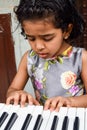 Asian cute girl playing the synthesizer or piano. Cute little kid learning how to play piano Royalty Free Stock Photo