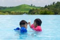 Asian cute little toddler boy and girl in swimming suit relaxing in a pool Royalty Free Stock Photo