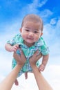 Asian cute new born baby smile happily with holding hands mother on blue sky background. Royalty Free Stock Photo