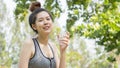 Asian cute sport healthy fit and firm slim teen lady hold plastic bottle of water on the hand in summer hot day at outdoor garden.