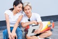 Asian cute woman sitting on skateboards, handsome man sitting on street around skateboard way, smile, and they are happy using Royalty Free Stock Photo