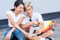 Asian cute woman sitting on skateboards and touch screen on tablet, handsome man sitting on street around skateboard way, and Royalty Free Stock Photo