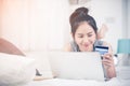 Asian cute woman using laptop computer shopping online on the be Royalty Free Stock Photo