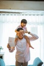 asian dad shoulders piggybacks his son showing paper love drawing