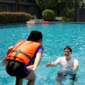 An Asian dad takes a vacation with his family in the pool, preparing to catch his daughter who will jump into the water